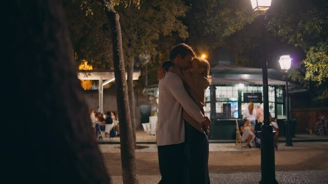 Cute lovers embracing date on night illuminated street. Happy family enjoying