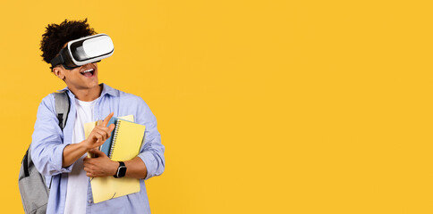 Delighted student with VR headset and books on yellow, copy space