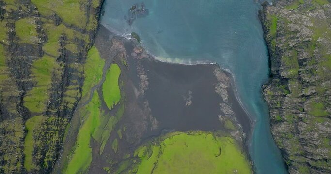 Aerial Top Upward Shot Of Rippled Sea Amidst Green Rock Formations - Saksun, Faroe Islands