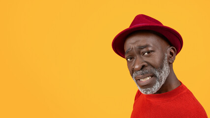 Skeptical black senior man with a questioning expression, wearing a red sweater and hat