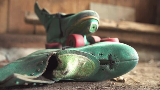 Old green roller skates with red wheels in shed / Focus on side skate