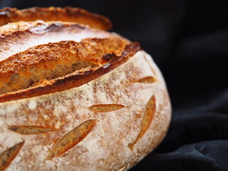 Closeup on a homemade rustic sourdough loaf on black background