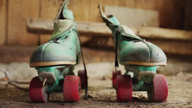 Old green roller skates with red wheels in shed / Side by side