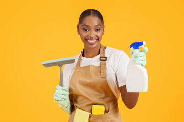 Professional African American cleaner with squeegee scrubber and detergent, studio
