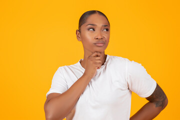 pensive african american lady thinking over yellow studio background