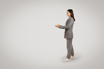 Side view of woman in suit extending hand, grey background - obrazy, fototapety, plakaty