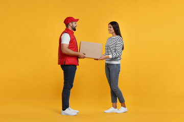 Smiling courier giving parcel to receiver on orange background