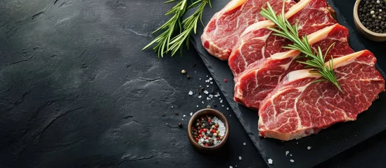Fotobehang Raw organic meat beef or lamb on a black slate board Top view with copy space. with copy space image. Place for adding text or design © vxnaghiyev