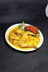Balinese Indonesian food, Ayam Betutu. Whole chicken filled with Balinese seasoning cassava leaves, wrapped in banana leaves and steamed. Served with Sambal Matah and Roasted Peanuts.