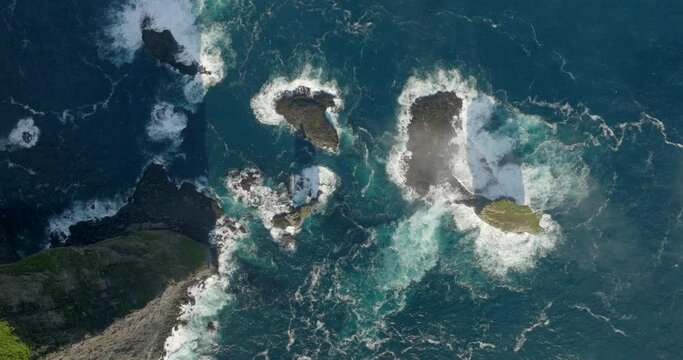 Aerial Top Shot Of Sea Waves Splashing On Rocks, Drone Flying Upwards During Sunny Day - Faroe Islands, Denmark