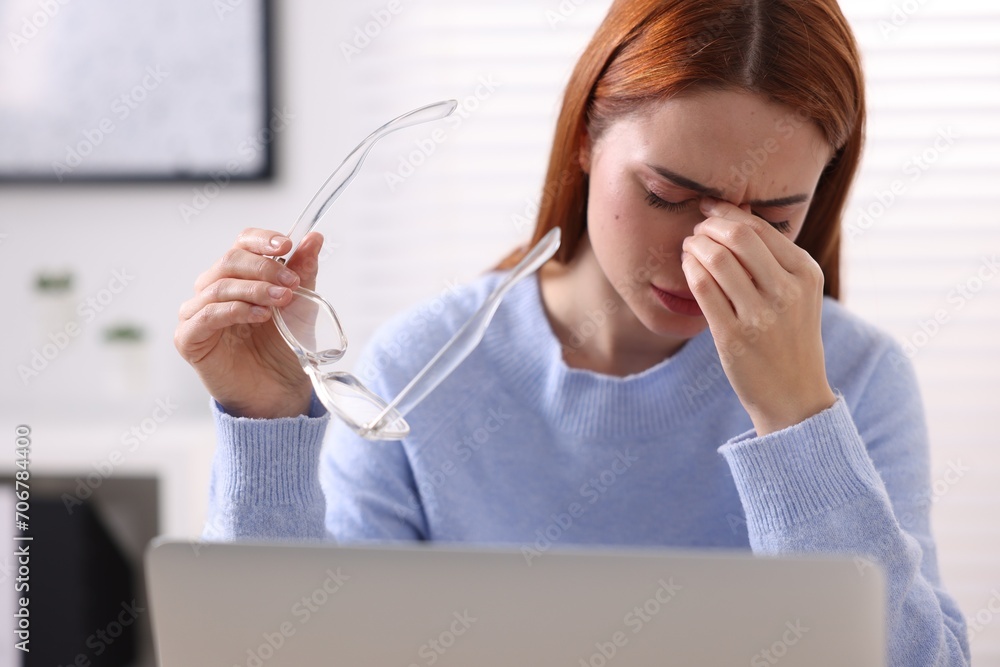 Wall mural woman with glasses suffering from headache at workplace in office