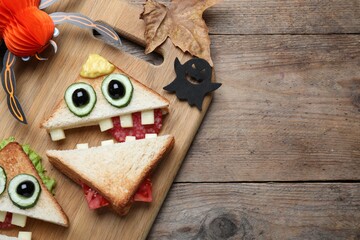 Cute monster sandwiches served on wooden table, flat lay with space for text. Halloween party food