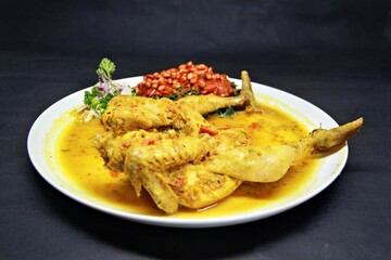 Balinese Indonesian food, Ayam Betutu. Whole chicken filled with Balinese seasoning cassava leaves, wrapped in banana leaves and steamed. Served with Sambal Matah and Roasted Peanuts.