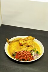 Balinese Indonesian food, Ayam Betutu. Whole chicken filled with Balinese seasoning cassava leaves, wrapped in banana leaves and steamed. Served with Sambal Matah and Roasted Peanuts.