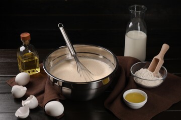 Composition with whisk and dough in bowl on wooden table