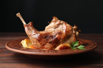 Tasty cooked rabbit meat with potatoes on wooden table, closeup