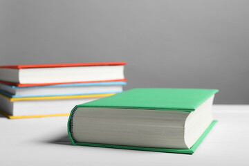 Different books on white table against gray background, closeup. Space for text