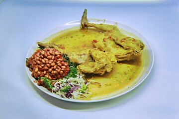 Balinese Indonesian food, Ayam Betutu. Whole chicken filled with Balinese seasoning cassava leaves, wrapped in banana leaves and steamed. Served with Sambal Matah and Roasted Peanuts.
