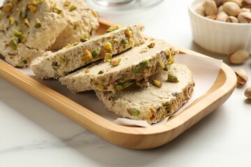 Tasty halva with pistachios on white marble table, closeup