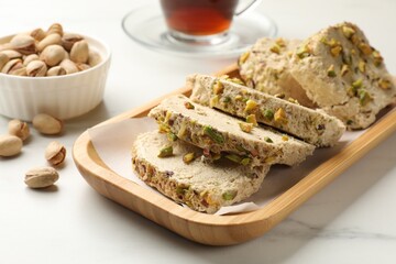 Tasty halva with pistachios on white marble table, closeup