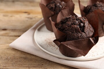 Tasty chocolate muffins on wooden table, closeup. Space for text