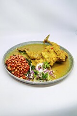 Balinese Indonesian food, Ayam Betutu. Whole chicken filled with Balinese seasoning cassava leaves, wrapped in banana leaves and steamed. Served with Sambal Matah and Roasted Peanuts.