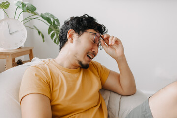 Laugh and shy asian man in yellow t-shirt on bean bag. Charming and relaxing.