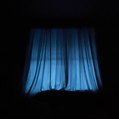 Blue hour light shining through thin curtains