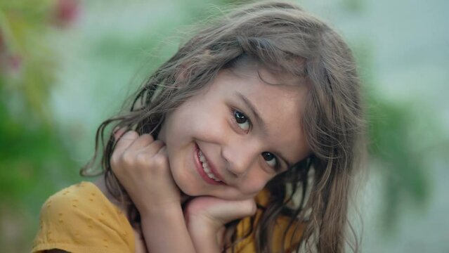 Close-up of a playful 5-year-old girl making silly smiles during her tropical summer vacation, capturing the carefree spirit of childhood