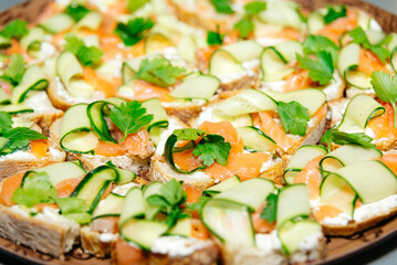 Elegant Smoked Salmon and Cucumber Canapes. Smoked salmon canapes with cream cheese, cucumber, and fresh parsley, presented on a tray for a sophisticated appetizer.