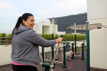 40-year-old Latina woman exercises in the roof garden of her condominium accompanied by her...