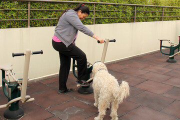 40-year-old Latina woman exercises in the roof garden of her condominium accompanied by her...