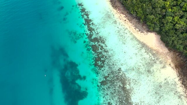 Aerial tilt up shot of turquoise clear ocean and tropical island of Ko Rok Noi in Thailand