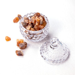 Crushed brown candy sugar in a transparent glass sugar bowl on the table - 706802008