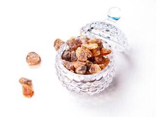 Crushed brown candy sugar in a transparent glass sugar bowl on the table - 706802020