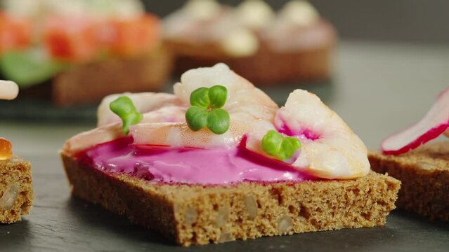 Smorrebrod, traditional Danish Scandinavian open sanwiches with fish, dark rye bread with herring and salmon, different topping, norwegian and swedish cuisine. Chef cooking tapas in cafe. 