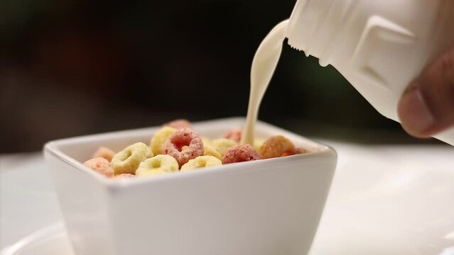 Pour milk over colorful cornflakes or cereal. Put in a white bowl healthy food
