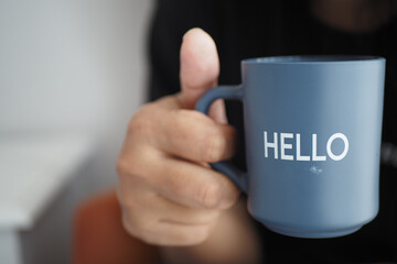 women holding a blue coffee cup with hello word