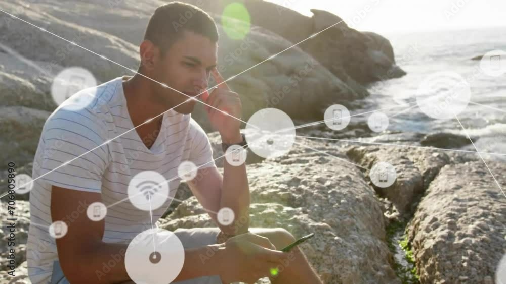 Poster animation of network of connections with icons over biracial man using smartphone by sea
