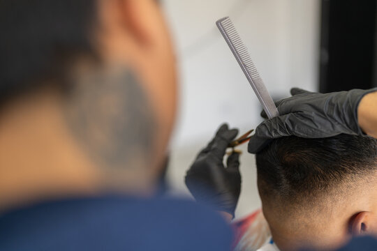 Barber using scissors to trim the hair of a client