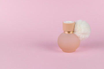 A bottle of women's perfume on a light pink background.
