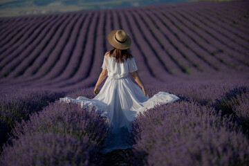 Back view woman lavender sunset. Happy woman in white dress holds lavender bouquet. Aromatherapy concept, lavender oil, photo session in lavender