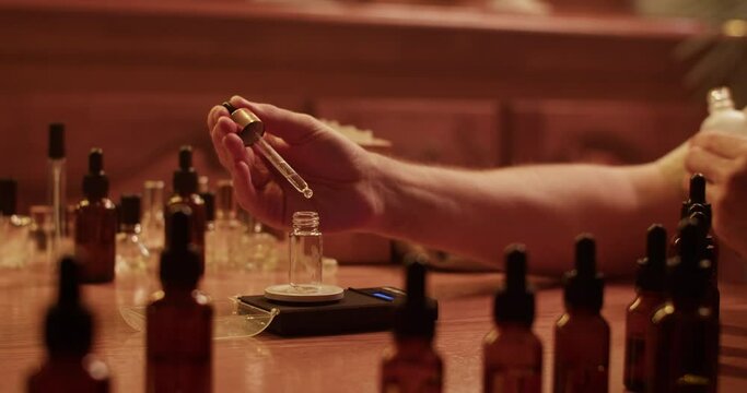 Cropped perfumer measuring weight of oil drop
