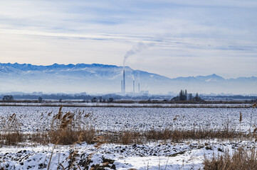 Panorama of a snow-covered mountain valley  and the smoking chimneys of the thermal power plant in the city of Bishkek, Kyrgyzstan. Atmospheric pollution, smog, climate change.