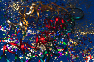 Golden Mardi Gras or carnival face mask  on a blue background with colored tinsel and confetti.Selective focus. Venice Carnival.