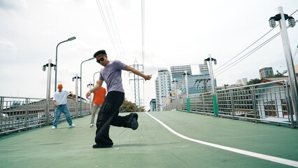 Low angle camera of hipster doing freeze pose while looking at camera. Group of break dancer...