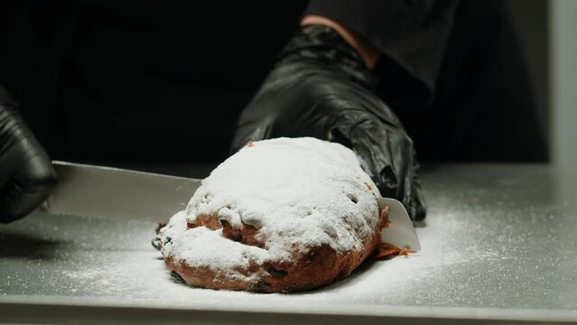 German Stollen bakery dessert close-up. Bun with spices, raisins, nuts and candied fruits and powdered sugar on top. Christmas desserts. Bakehouse