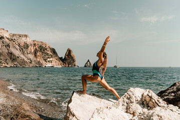 Fototapeta na wymiar Yoga on the beach. A happy woman meditating in a yoga pose on the beach, surrounded by the ocean and rock mountains, promoting a healthy lifestyle outdoors in nature, and inspiring fitness concept.