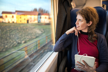 Serene Handsome Woman Working  on a Tablet While Traveling in Relax with Public Train Transport