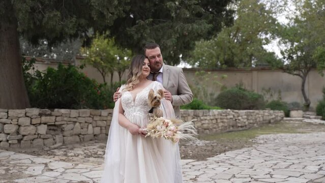 A bride and groom pose for wedding photo with their little dog.